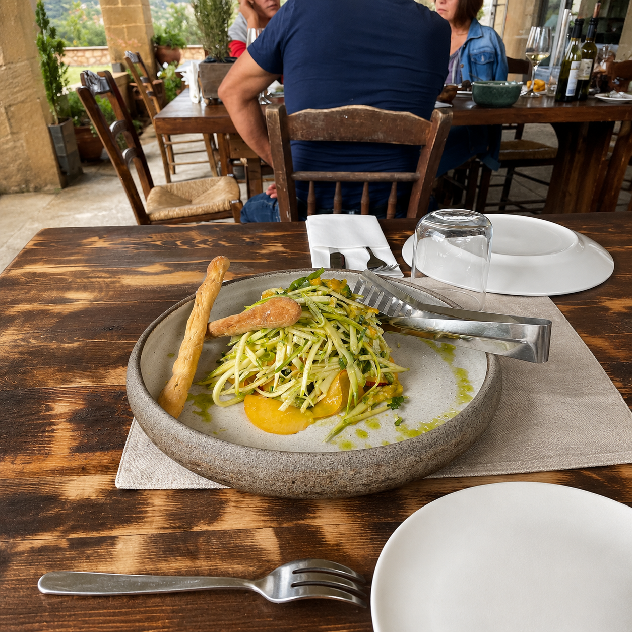 Fresh zucchini salad plated in a rustic bowl on an outdoor restaurant table in Crete