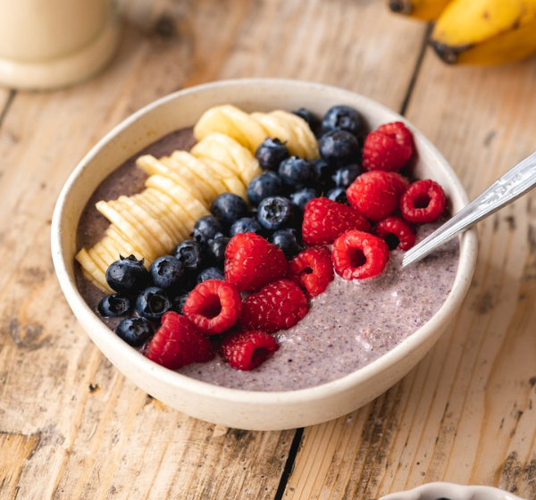 Bowl of healthy instant gluten-free porridge mix – acai, banana, strawberry, buckwheat, and flax seeds. 